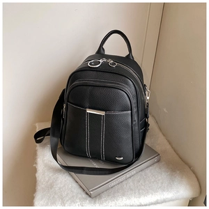 Detail of black textured leather backpack with contrast white stitching and metal zippers