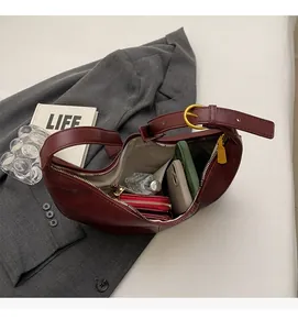 Interior view of spacious burgundy crescent bag showing storage for phone and perfume