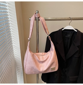 Close-up of pink hobo tote bag featuring vintage PU leather texture and metal brand plaque