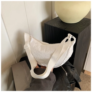 Close-up of a white nylon crescent bag with textured fabric on a minimalist display