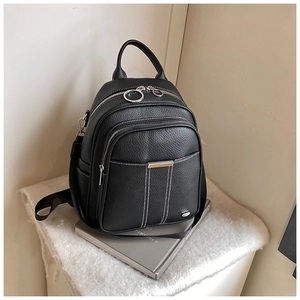Close-up of black lychee leather backpack with silver metal zippers and white stitching