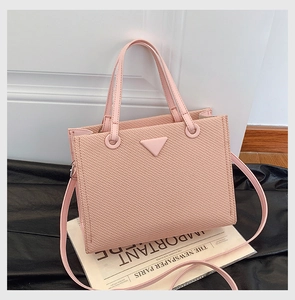 Detail of pink woven texture tote bag with triangular plaque on newspaper background