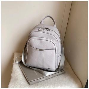Detail of light gray lychee grain leather backpack with silver zippers and metal accents