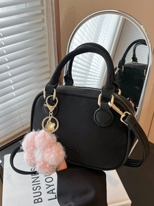 Black suede-textured pillow bag with gold hardware and pink flower plush charm