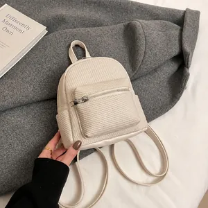 Detail shot of the woven texture and silver hardware on this cream mini backpack