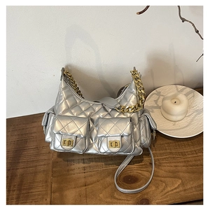 Detailed view of silver quilted shoulder bag with multiple pockets and gold chain on wooden table