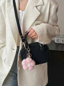 Chic black mini pillow bag with plush flower charm and gold hardware on white blazer