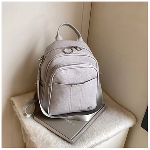 Detail of light grey pebbled leather backpack with silver zippers and metal accents