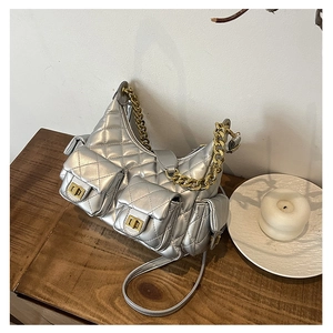 Close-up of quilted silver shoulder bag with multiple pockets and gold chain on wood