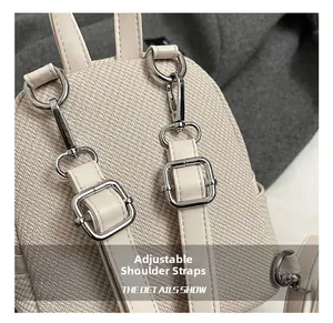 Detail of adjustable straps and silver metal hardware on beige woven mini backpack