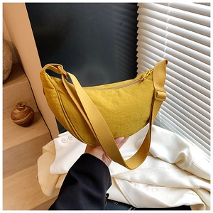 Detail of ginger yellow nylon crescent bag with wide adjustable strap and zipper closure