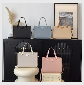 Detail view of five Saffiano leather tote bags in various colors with golden hardware