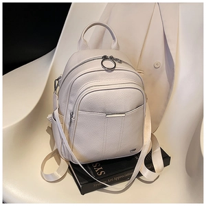 Detail of a minimalist off-white pebble leather backpack on a stylish lounge chair