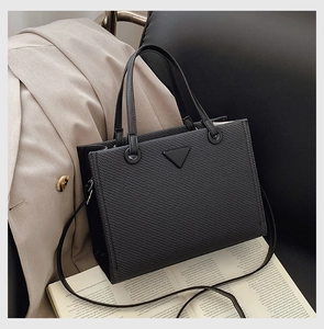 Close-up of black woven tote bag with triangular accent on lifestyle background