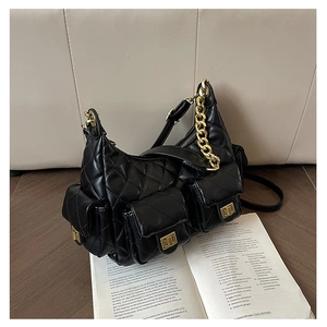 Detail of black quilted hobo bag with gold hardware on an open book background