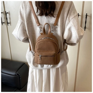Detailed view of brown woven texture small backpack with silver zippers and slim straps