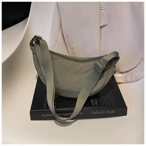 Detailed close-up of olive green nylon crescent bag on books with textured fabric surface