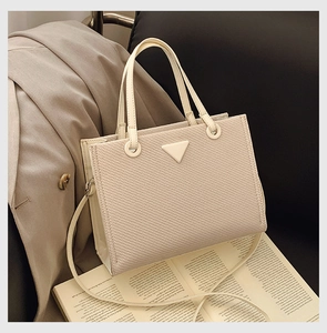 Detail of beige woven tote bag with triangular accent and slim shoulder strap
