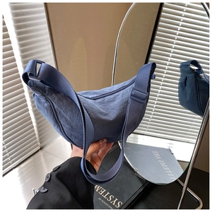 Detailed close-up of blue nylon crescent bag with adjustable strap and zip closure
