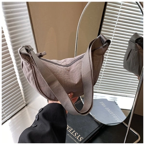 Detail of grey-purple nylon crescent bag with wide strap reflecting in a stylish mirror