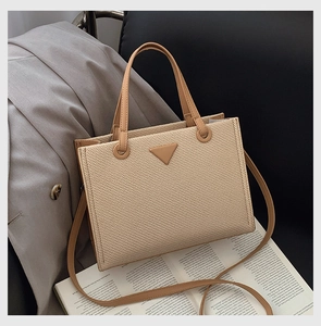 Detail of woven texture tote bag with leather strap and iconic triangular patch