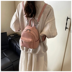 Detail of pink mini backpack featuring textured surface and silver metal zipper on model