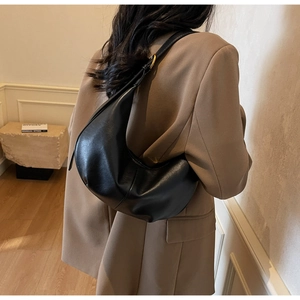 Detail shot of black leather crescent bag with elegant gold buckle on the shoulder strap