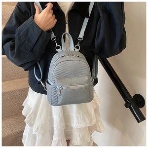 Close-up of mini vintage backpack featuring blue herringbone weave texture and silver zippers