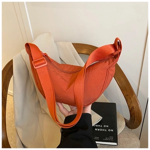 Macro view of bright orange nylon crescent bag with textured surface and wide shoulder strap