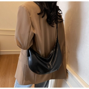 Side view of a black crescent tote bag on shoulder with smooth glossy leather finish