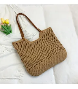 Close-up of hollow mesh straw beach bag with premium brown leather shoulder straps