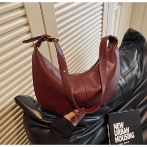 Detail of burgundy half-moon hobo bag showing glossy leather texture and gold hardware