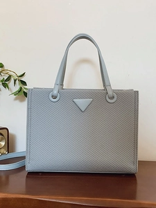Chic light blue tote bag with a metallic logo on a wooden table in a lifestyle setting