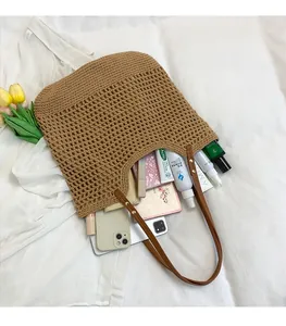 Flat lay of khaki woven straw tote bag with brown leather straps and spacious interior