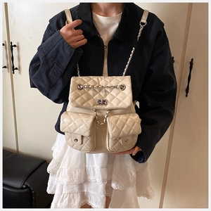 Detail of a cream quilted backpack with chain straps and dual front flap pockets