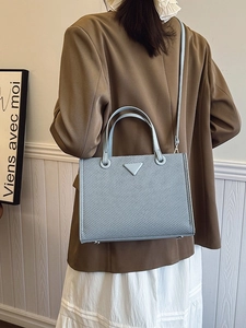 Light blue woven textured tote bag with top handles and detachable crossbody strap