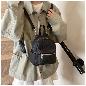 Close-up of black mini backpack featuring a textured woven pattern and silver metal zippers