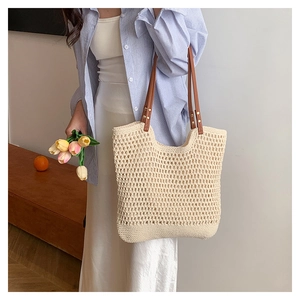 Detail of hollow-out woven beach bag with premium brown leather handles and metal rivets