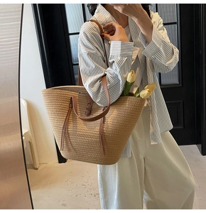 Detail of straw tote bag with dual leather handles and elegant tulip decoration