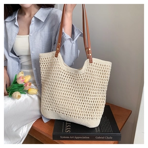 Detail of hollow woven tote bag with brown leather straps and metal rivets decoration