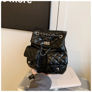 Detail of black quilted leather backpack with metal chain and twist-lock closure