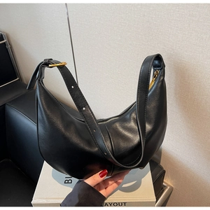 Detailed macro view of black hobo bag with pebble leather texture and gold hardware