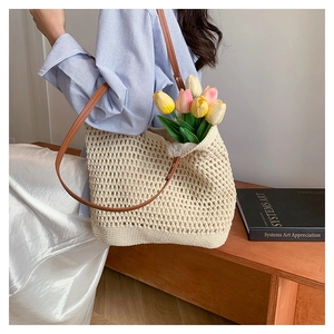 Detail of beige hollow woven shoulder bag with brown leather straps and colorful tulips