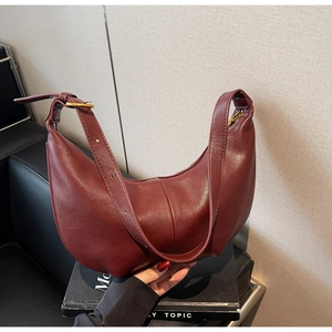 Detail view of burgundy crescent shoulder bag with smooth texture and golden metal zipper