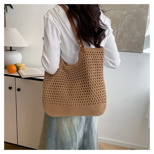 Detail of hollow woven texture and brown leather straps on a beach tote bag