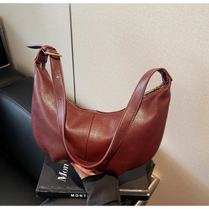 Close-up of wine red crescent bag with grainy leather texture and gold hardware details