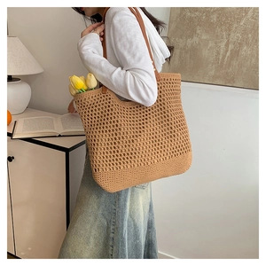 Detailed view of handmade hollow woven tote bag with brown leather shoulder straps