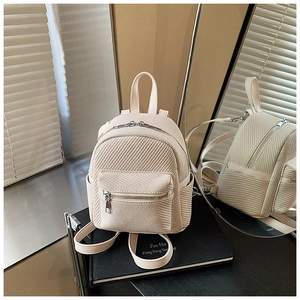 Close-up of cream mini backpack featuring textured woven leather and silver zipper detail