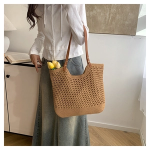 Detail of hollow-out straw woven tote bag with brown leather straps and yellow tulips