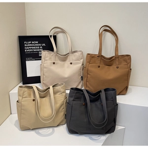 Detailed view showing large canvas tote bags in four neutral colors with pockets and straps
